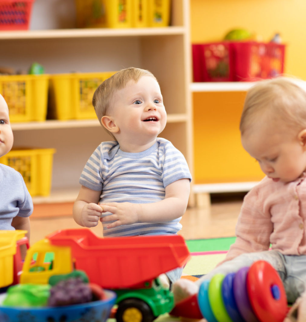 Little toddlers boys and a girl playing together in kindergarten or creche. Preschool children in day care centre