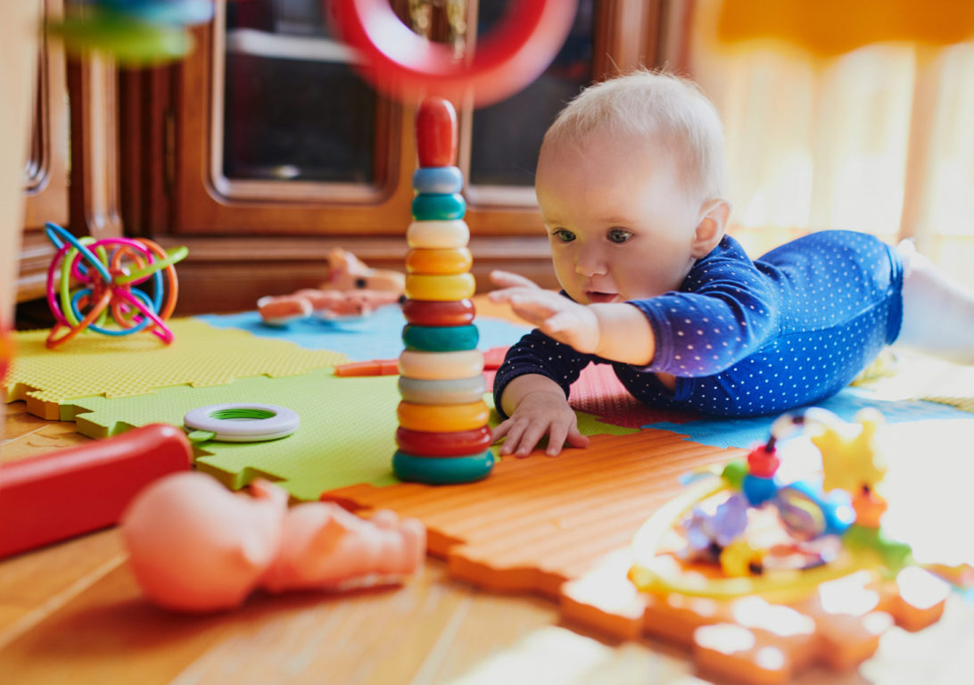 Baby girl playing with toys on the floor. Happy healthy little child at home