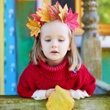 Beautiful autumn portrait of adorable preschooler girl in colorful maple leaves wreath on her head